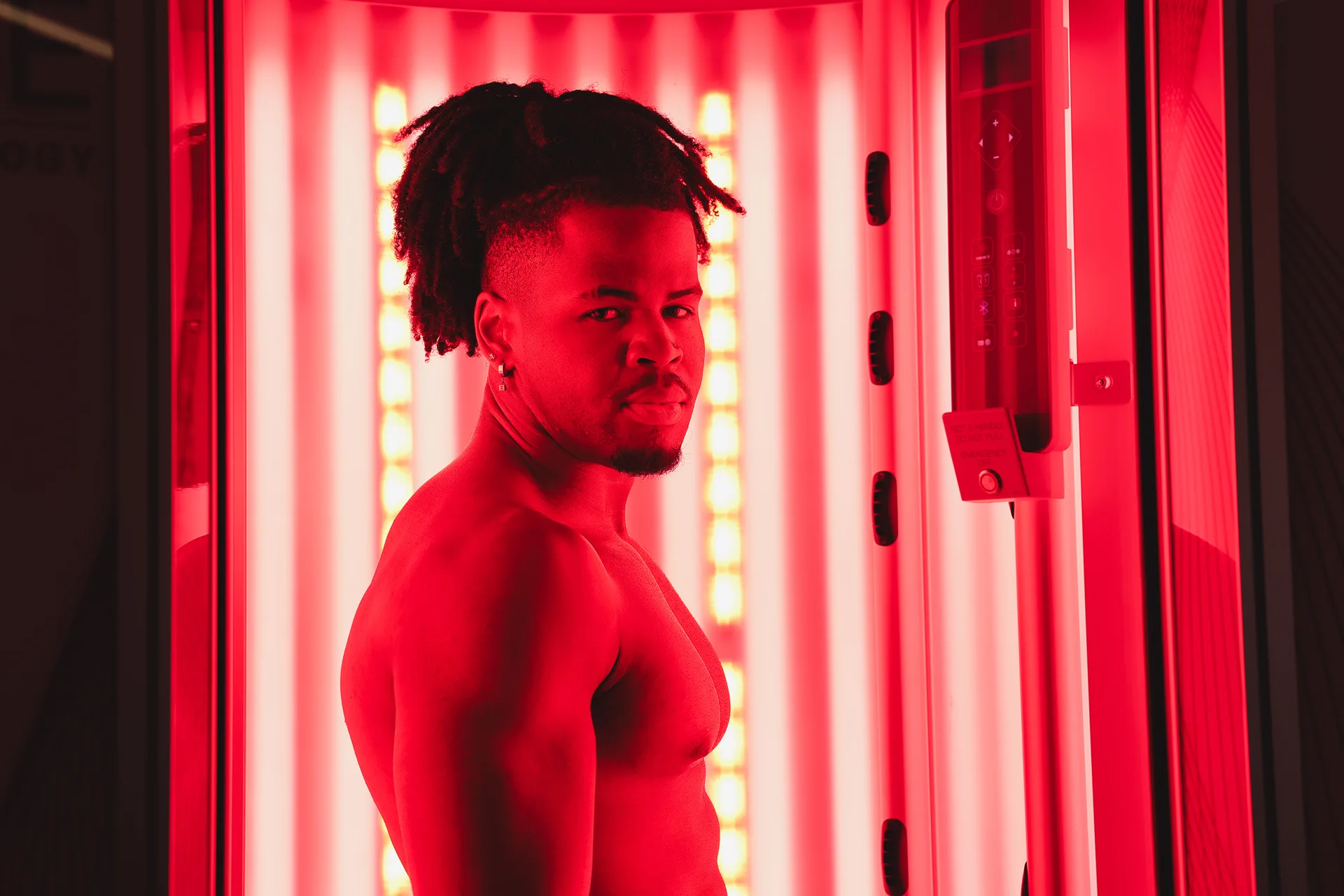 Muž relaxující v otevřeném červeném soláriu RedWave Plus během terapie